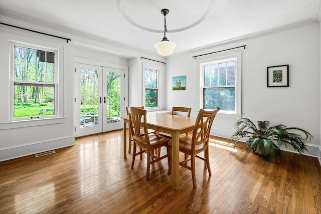 dining room featuring french doors, baseboards, visible vents, ornamental molding, and hardwood / wood-style flooring