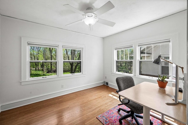 home office with baseboards, plenty of natural light, wood finished floors, and visible vents