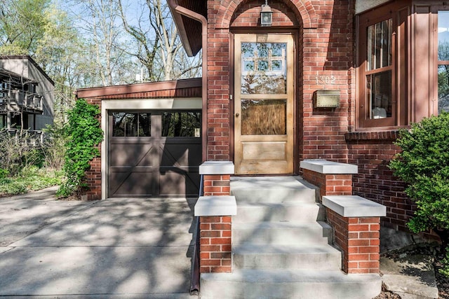 entrance to property featuring concrete driveway, brick siding, and a garage