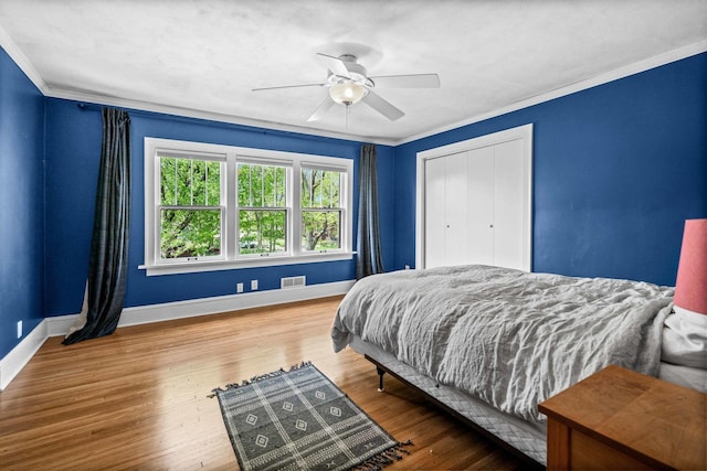 bedroom featuring crown molding, baseboards, wood finished floors, and visible vents