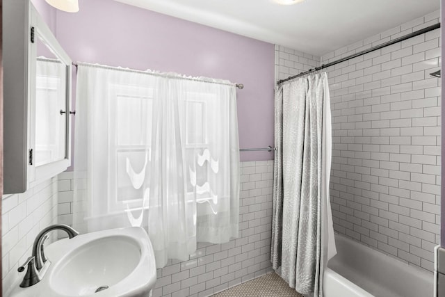 bathroom with tile walls, a sink, and shower / tub combo