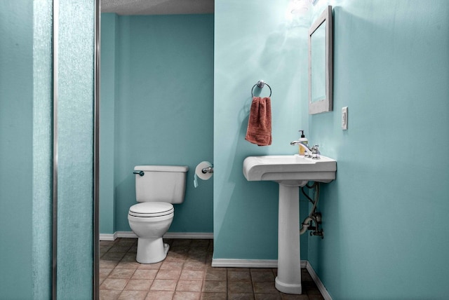 bathroom with toilet, baseboards, and a sink