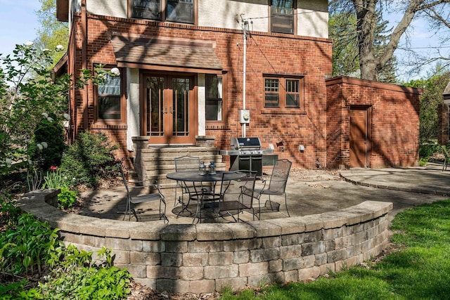 rear view of property featuring brick siding, a patio area, french doors, and an outdoor kitchen