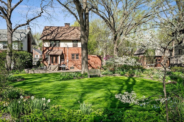 rear view of property featuring a yard, brick siding, and a chimney