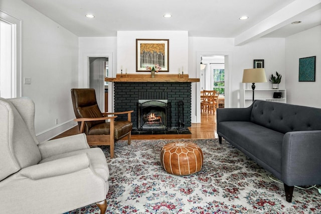 living room with recessed lighting, a brick fireplace, and wood finished floors