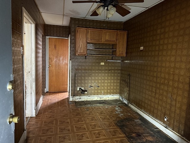 laundry area with a ceiling fan and dark floors