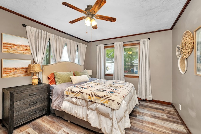 bedroom with baseboards, ornamental molding, a ceiling fan, and light wood-style flooring