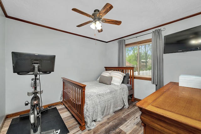 bedroom with baseboards, ornamental molding, a ceiling fan, and wood finished floors