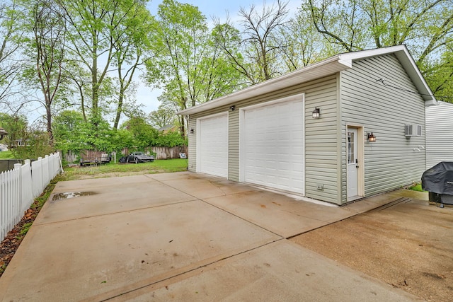 detached garage with fence and a wall mounted air conditioner