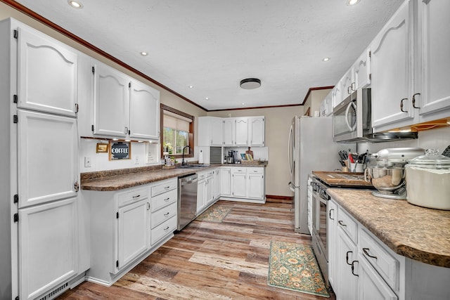 kitchen with a sink, white cabinets, ornamental molding, and stainless steel appliances