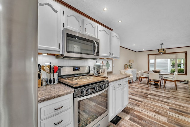 kitchen featuring white cabinets, appliances with stainless steel finishes, ornamental molding, and light wood finished floors