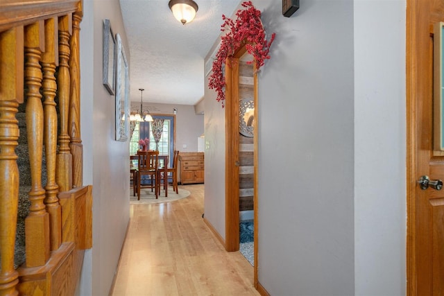 1107 N Bailey Dr, Pontiac, IL 61764 - corridor with light wood-type flooring, a chandelier, and a textured ceiling