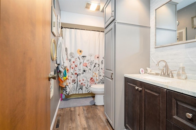 1107 N Bailey Dr, Pontiac, IL 61764 - bathroom featuring toilet, wood finished floors, backsplash, vanity, and a shower with shower curtain