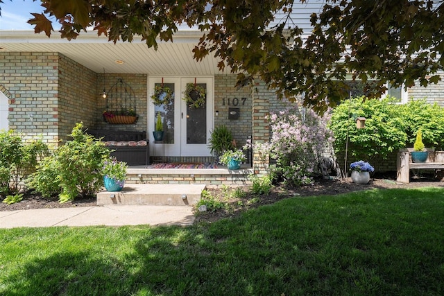 1107 N Bailey Dr, Pontiac, IL 61764 - view of exterior entry with brick siding, french doors, a lawn, and covered porch