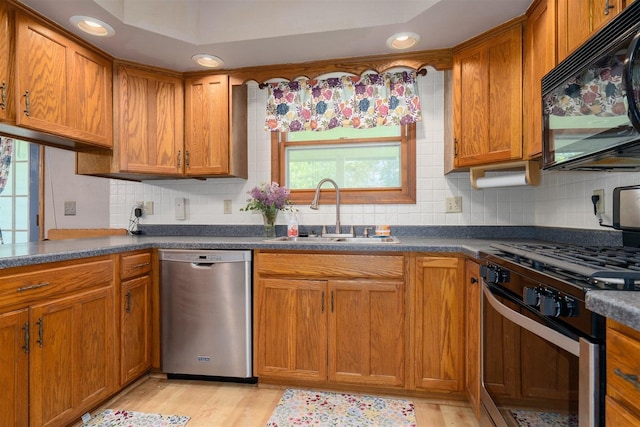 1107 N Bailey Dr, Pontiac, IL 61764 - kitchen with stainless steel appliances, a sink, decorative backsplash, brown cabinets, and dark countertops