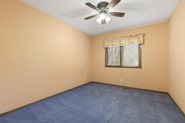 empty room with a ceiling fan, baseboards, and dark colored carpet