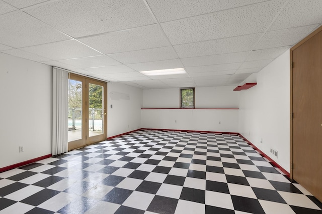 spare room featuring tile patterned floors, a drop ceiling, and baseboards