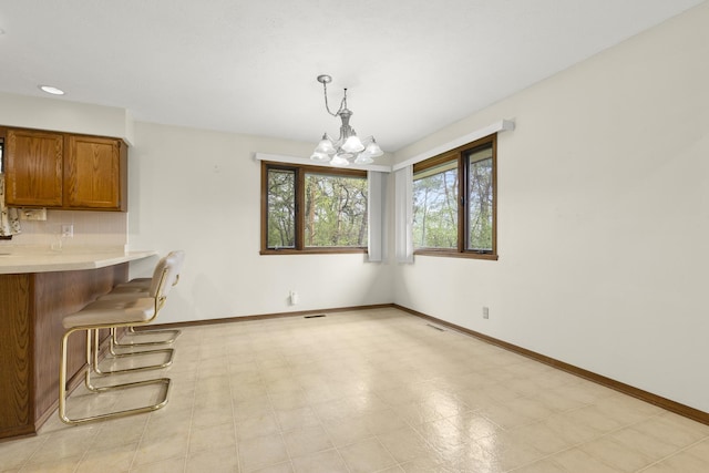 unfurnished dining area featuring an inviting chandelier, baseboards, and visible vents