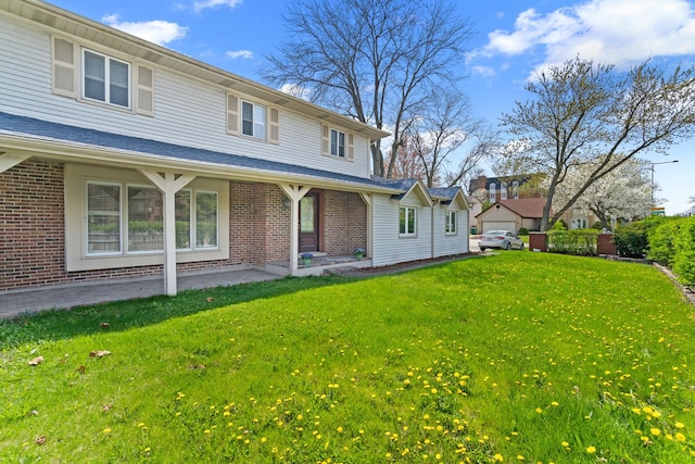 rear view of property with a yard and brick siding