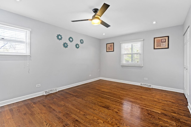 empty room with a ceiling fan, baseboards, visible vents, and dark wood-style floors