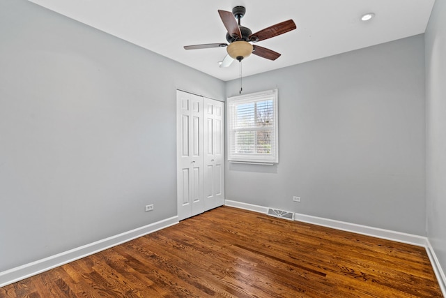 empty room featuring dark wood-style flooring, baseboards, visible vents, and ceiling fan