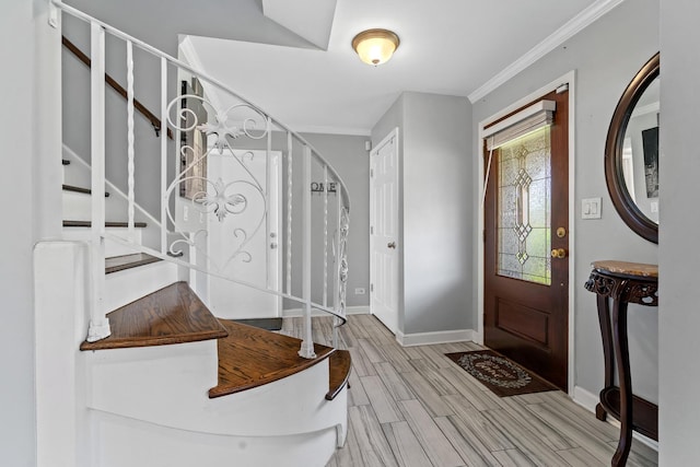 foyer with baseboards, ornamental molding, stairs, and wood finish floors