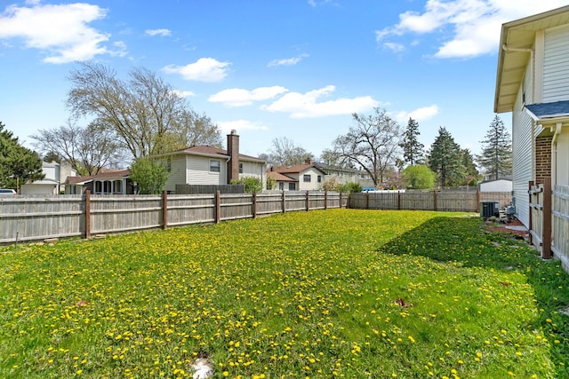 view of yard featuring a fenced backyard, a residential view, and central AC unit