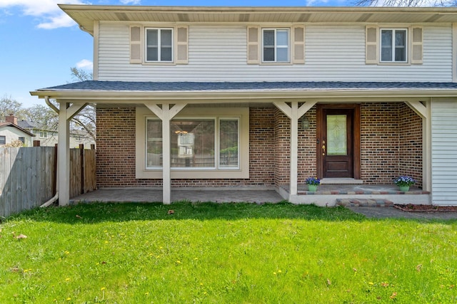 view of front of home featuring fence, a patio area, brick siding, and a front yard
