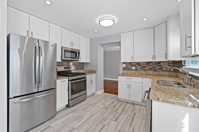kitchen featuring stainless steel appliances, white cabinetry, a sink, and tasteful backsplash