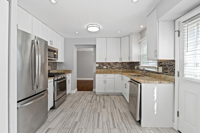 kitchen with a sink, appliances with stainless steel finishes, decorative backsplash, and a healthy amount of sunlight