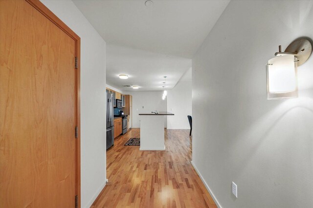 hall featuring light wood finished floors and baseboards