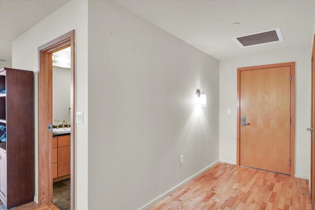 hallway featuring a sink, light wood-type flooring, and baseboards