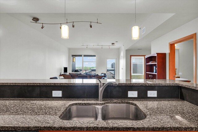 kitchen with a sink, dark stone countertops, and decorative light fixtures