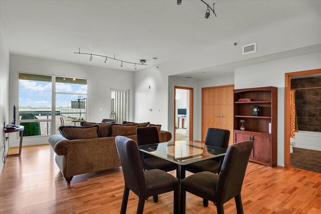 dining space with rail lighting and light wood-type flooring