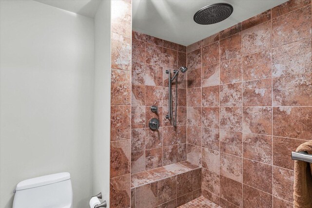 full bath featuring tiled shower and toilet