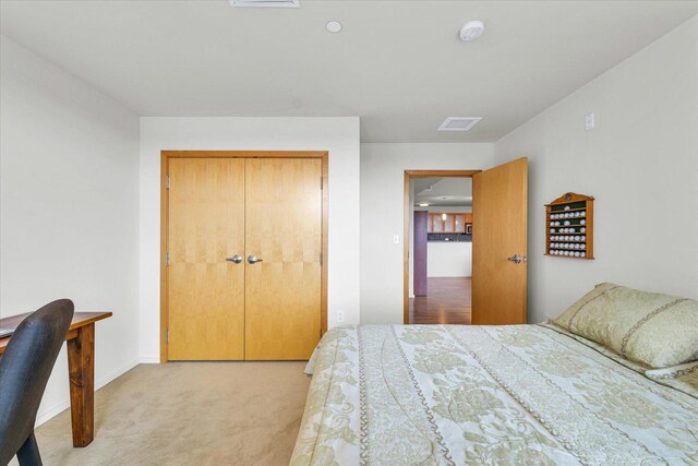 bedroom with light carpet, an office area, and a closet