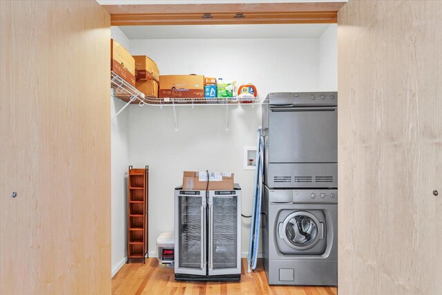 laundry room featuring wine cooler, stacked washer / drying machine, and wood finished floors