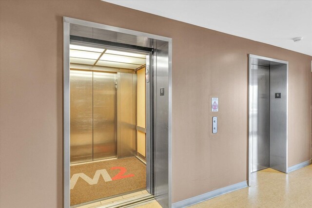 hall featuring elevator and baseboards
