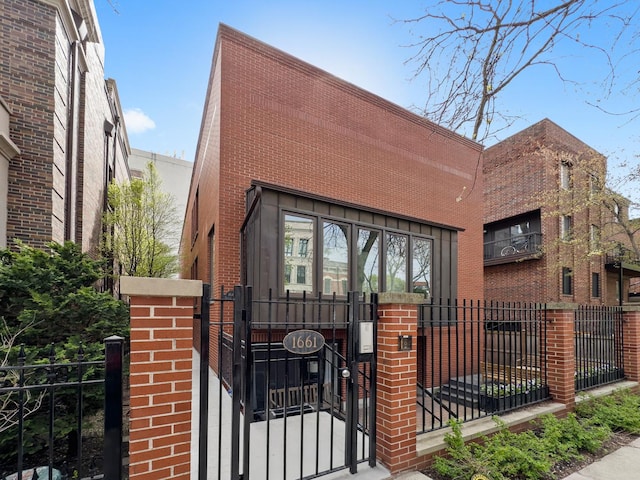 view of front of house with a gate, a fenced front yard, and brick siding