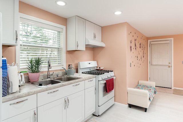 kitchen with under cabinet range hood, white cabinetry, white gas stove, and a sink