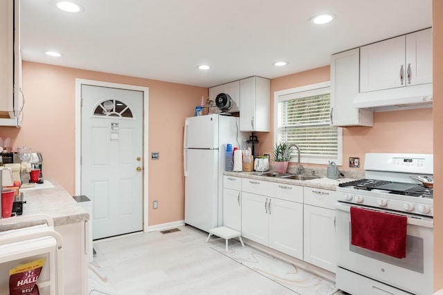 kitchen with a sink, light countertops, white cabinets, under cabinet range hood, and white appliances