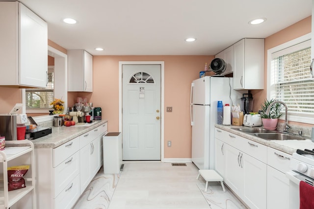 kitchen with recessed lighting, a sink, white cabinets, and white appliances