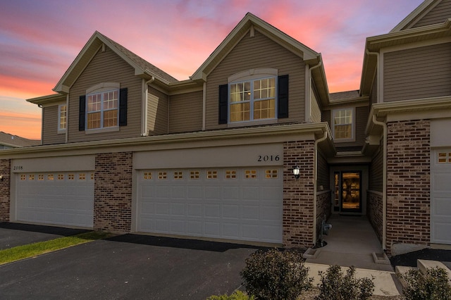 traditional-style home featuring brick siding, asphalt driveway, and a garage