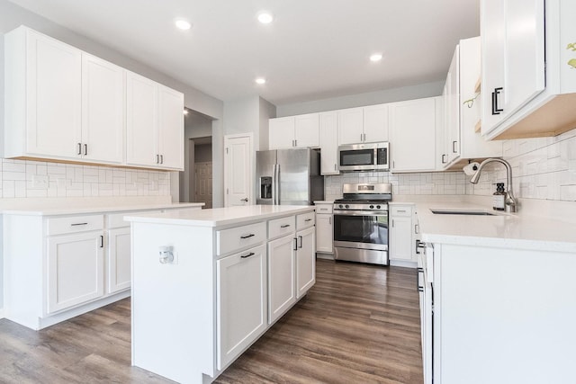 kitchen featuring appliances with stainless steel finishes, a sink, backsplash, a center island, and recessed lighting
