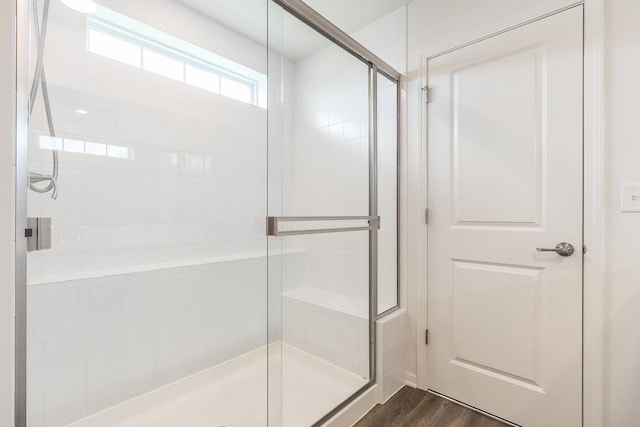 full bath featuring wood finished floors and a shower stall