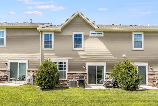 rear view of house with brick siding, a lawn, and central AC unit