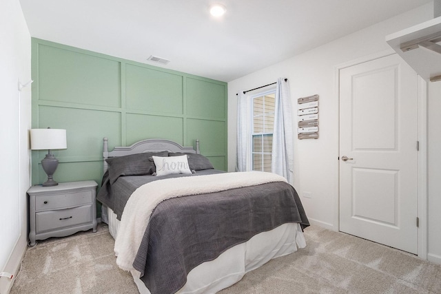 bedroom featuring a decorative wall and light carpet