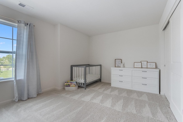 bedroom featuring multiple windows, light colored carpet, baseboards, and a closet