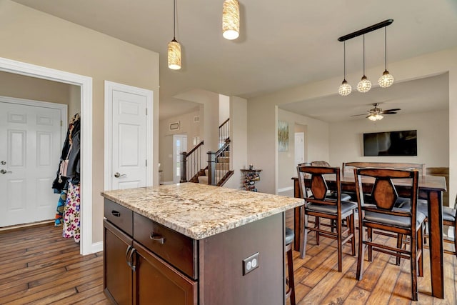 kitchen with baseboards, open floor plan, a ceiling fan, light wood finished floors, and hanging light fixtures