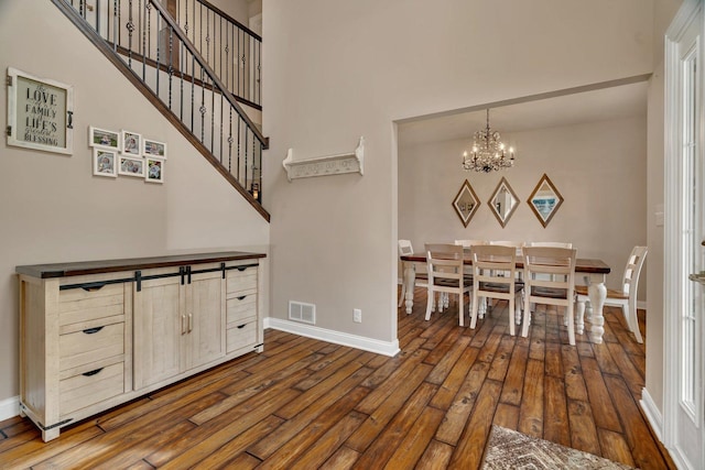 dining area with dark wood-style flooring, a high ceiling, a chandelier, baseboards, and visible vents